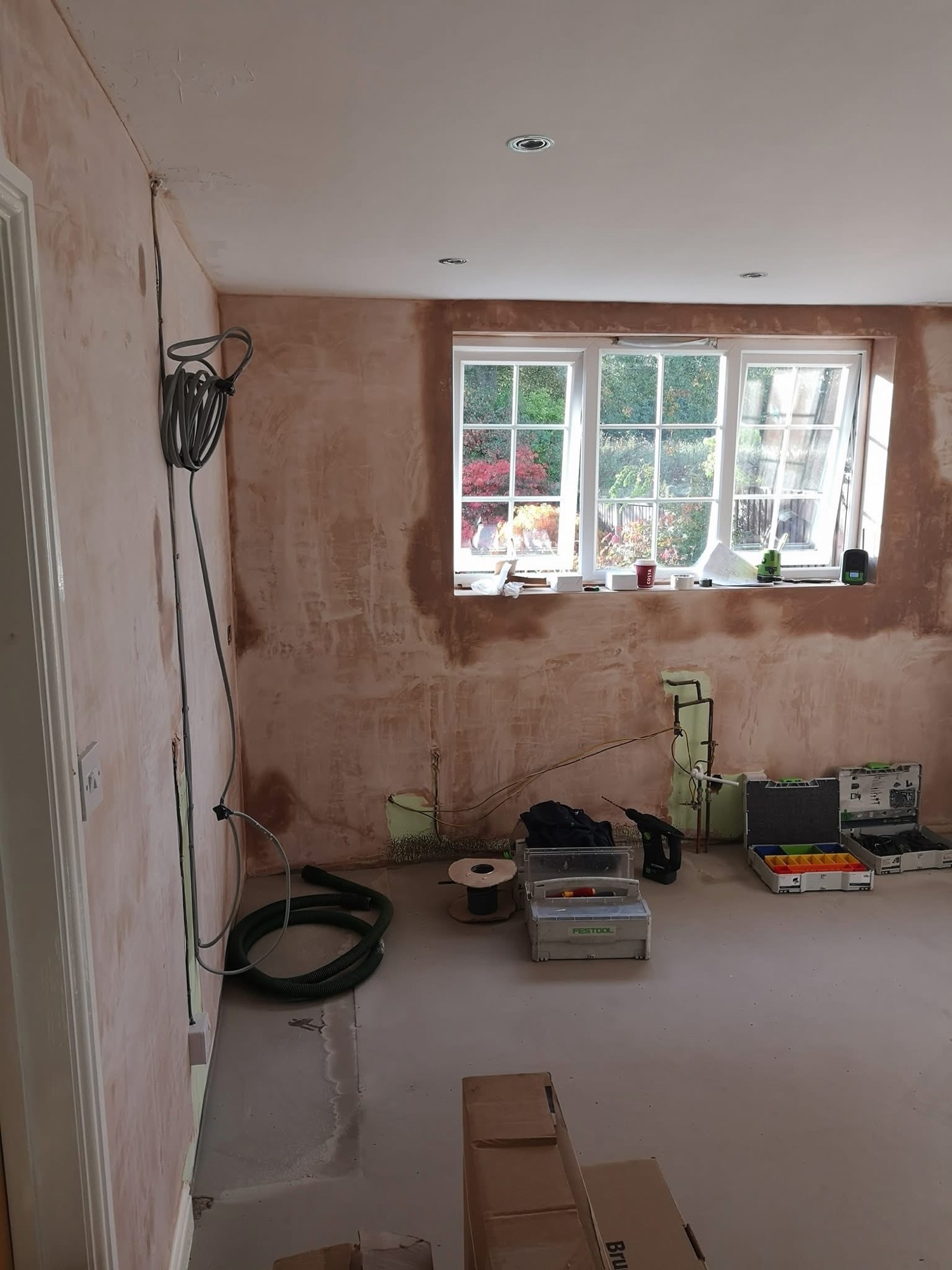 Empty room with bare plaster walls before kitchen installation