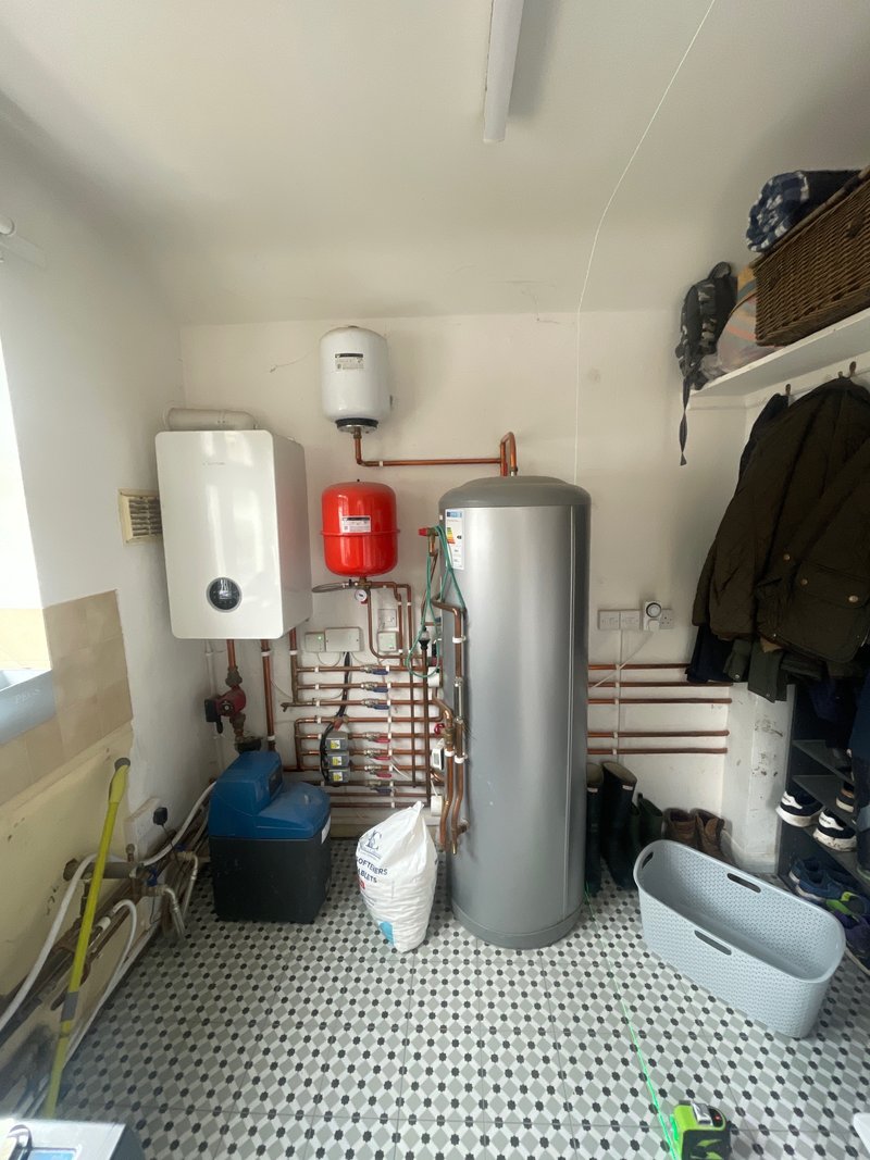 Utility room before works with exposed hot water cylinder and pipework